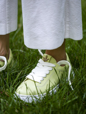 Close-up of soft pastel green leather and wide white laces on handmade sneakers