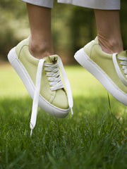 Pastel green leather sneakers with gold leaf detail on tongue, side view