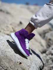 Stylish purple suede sneakers with wide white laces and gold accent