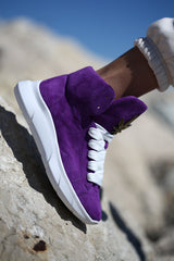 Close-up of purple suede sneakers, gold leaf embellishment, white sole